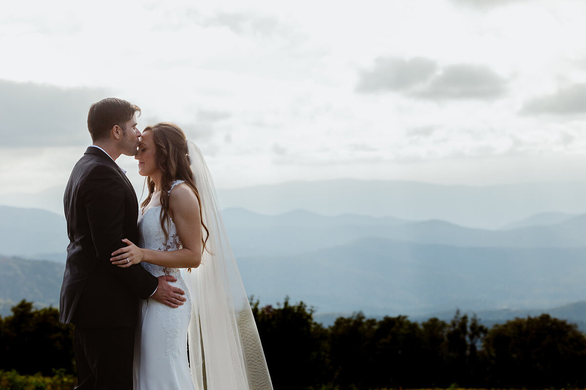 A person kissing their partner's head on their wedding day