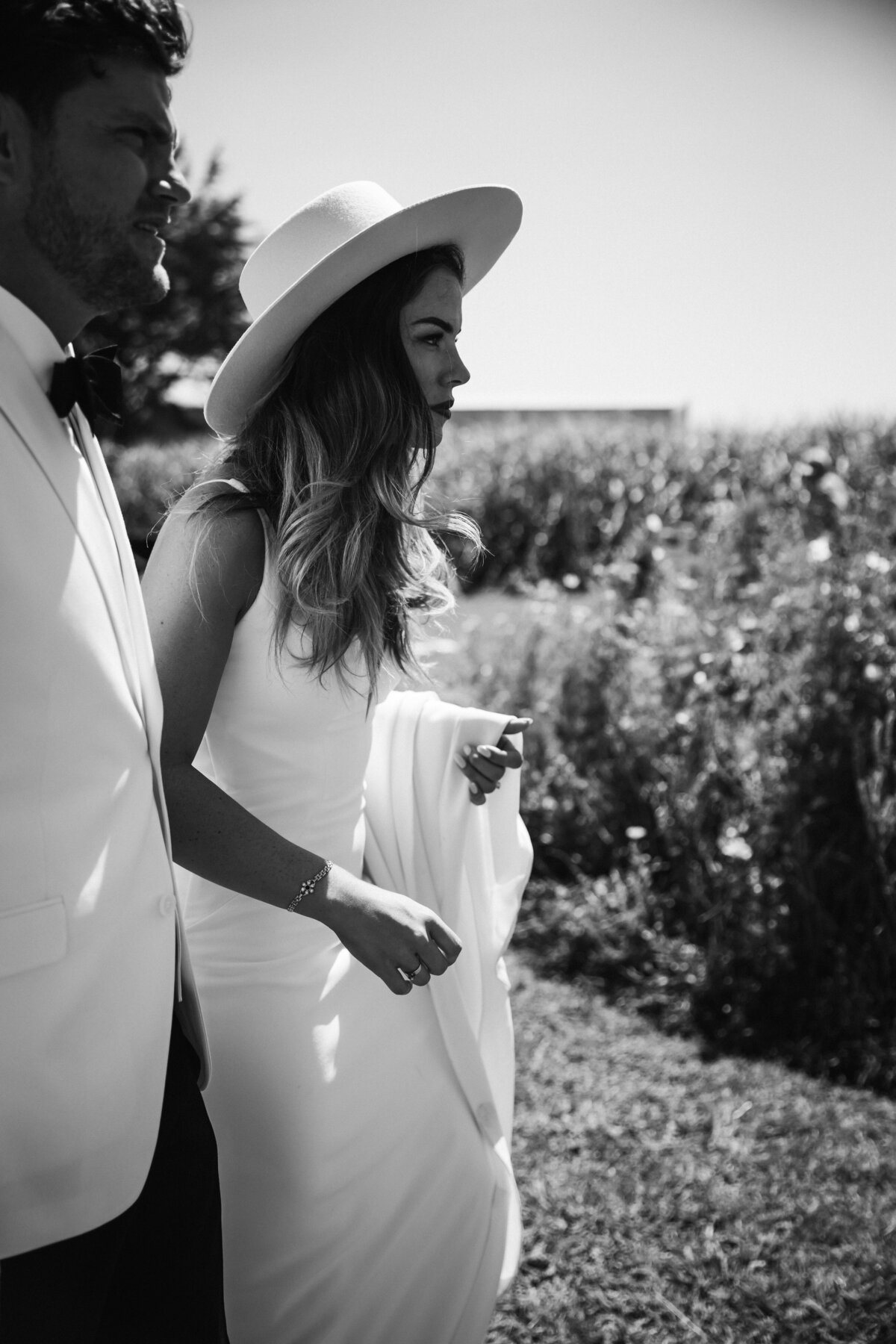 Kaitlyn and zac walking in the fields during their wedding photoshoot with taranaki photographer aimee kelly