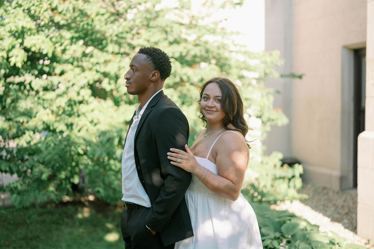 Kalamazoo outdoor engagement session with couple embracing on green lawn.