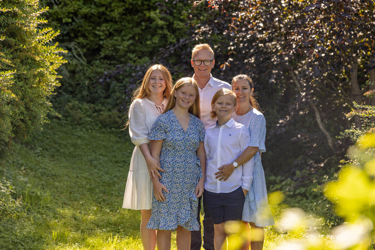 Familie på fem fotografert i en hage av Fotograf Linn Landmark.