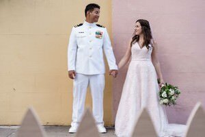 Military groom in dress whites with bride in wedding dress holding bouquet by colorful wall, St Augustine wedding photography