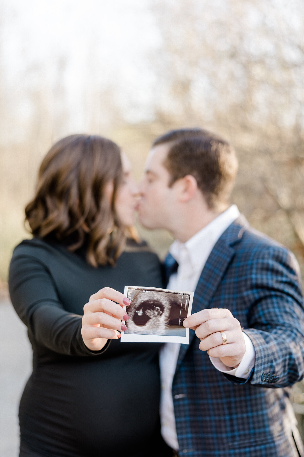 expecting parents kissing behind ultrasound for announcement photo