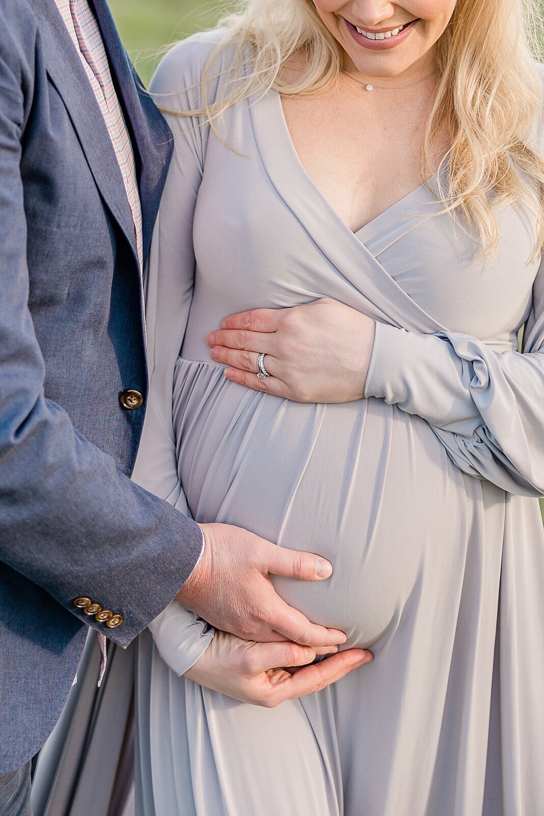 detail of mom smiling down at pregnant belly with hands