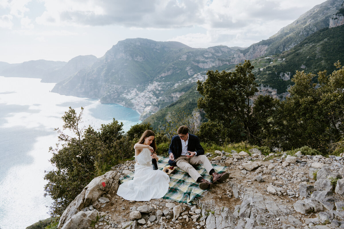 Couple setting up picnic on a cliff.