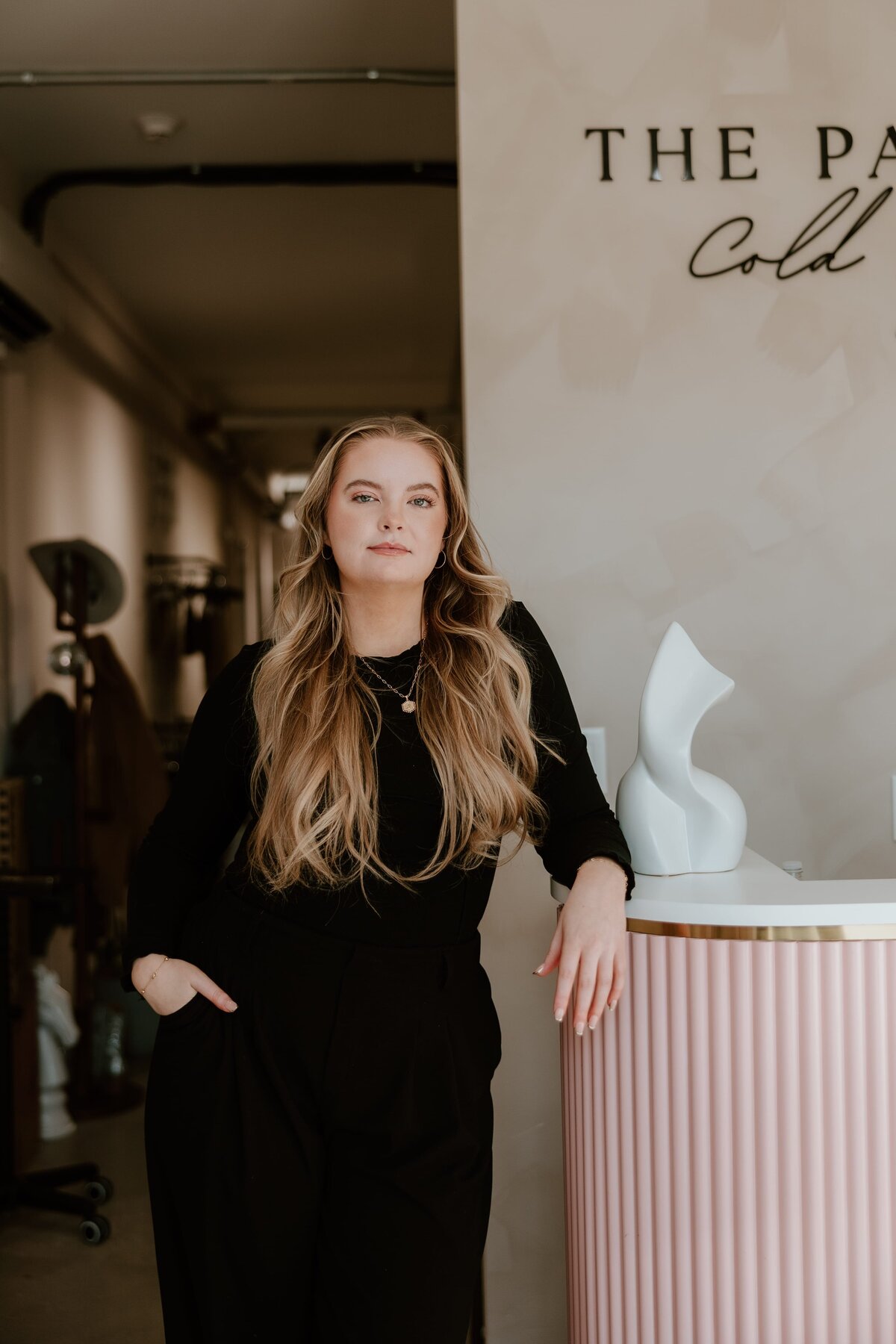 Professional branding portrait of a confident woman with long, wavy blonde hair, standing in a chic, modern salon captured by a Hudson Valley branding and headshot photographer.