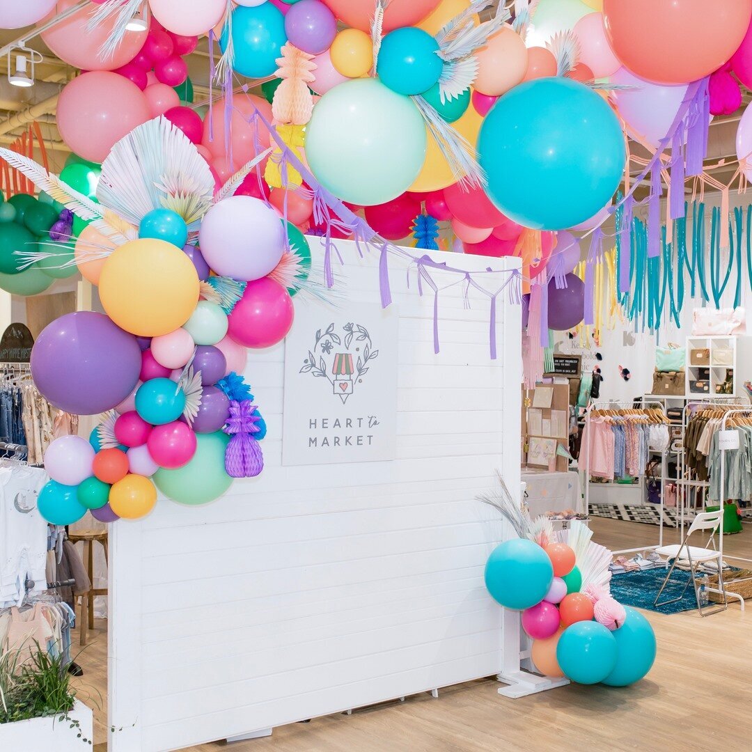 Heart to Market white backdrop with bright colorful balloon arch and streamers