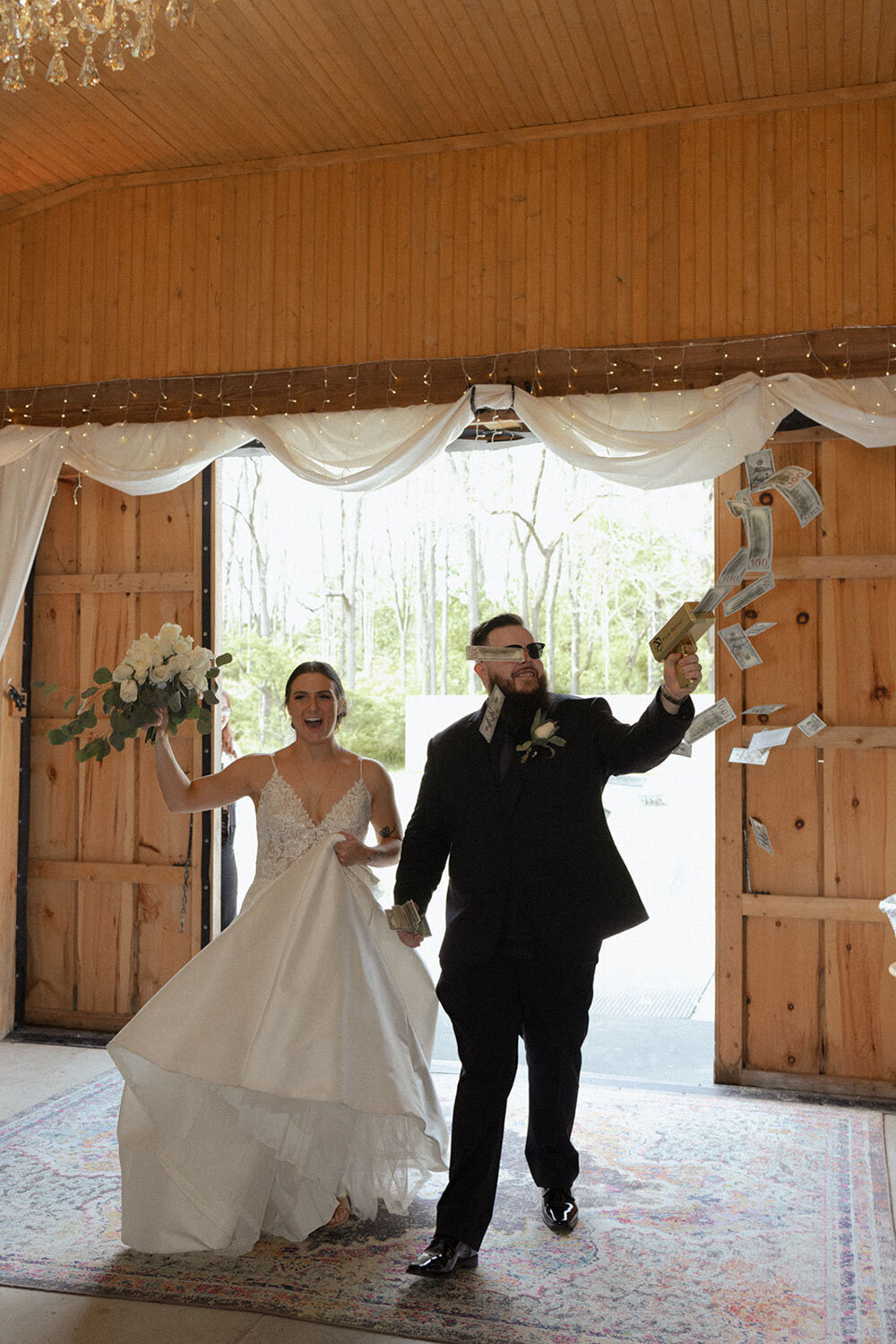 Bride and groom making a fun entrance with the groom holding a money gun