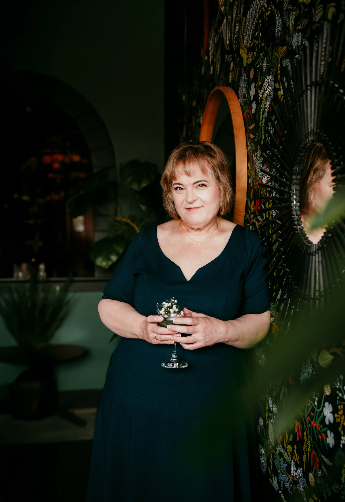 Elegant woman in navy dress sipping a cocktail at Bar Cart during online dating session