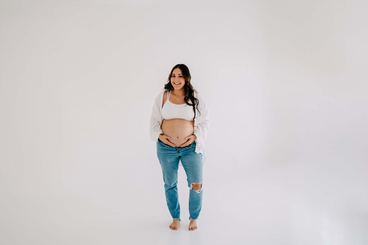 maternity photo of pregnant mom in jeans laughing in studio in Branson