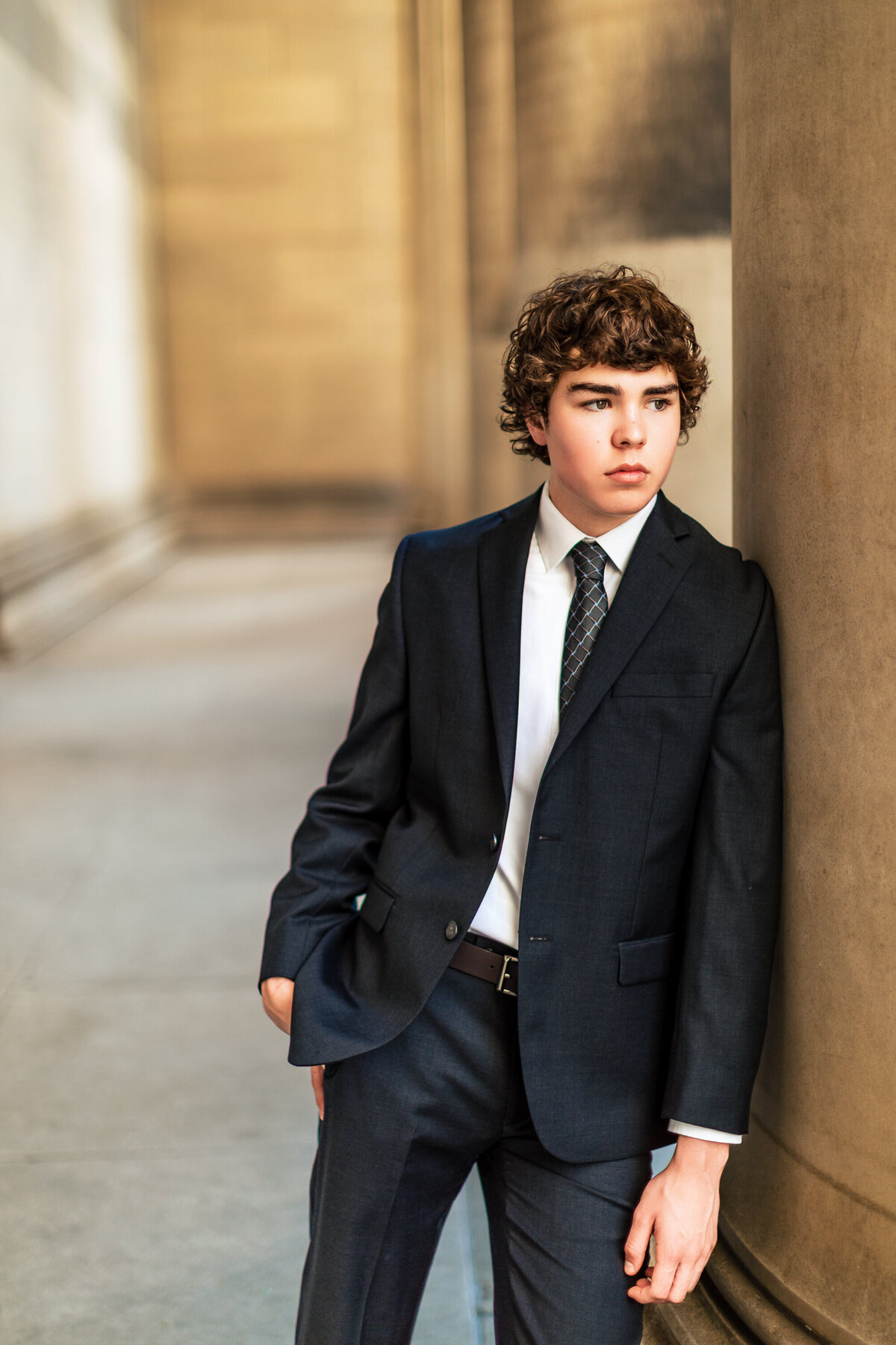 Senior photo session Pittsburgh PA with a teen boy leaning on the columns of the melon library.