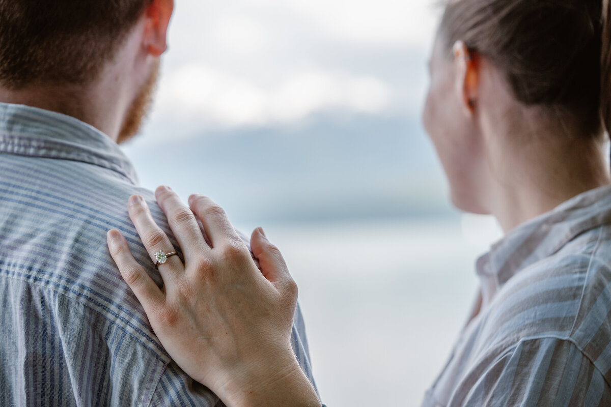 A person's hand on their partner's shoulder showing off a ring