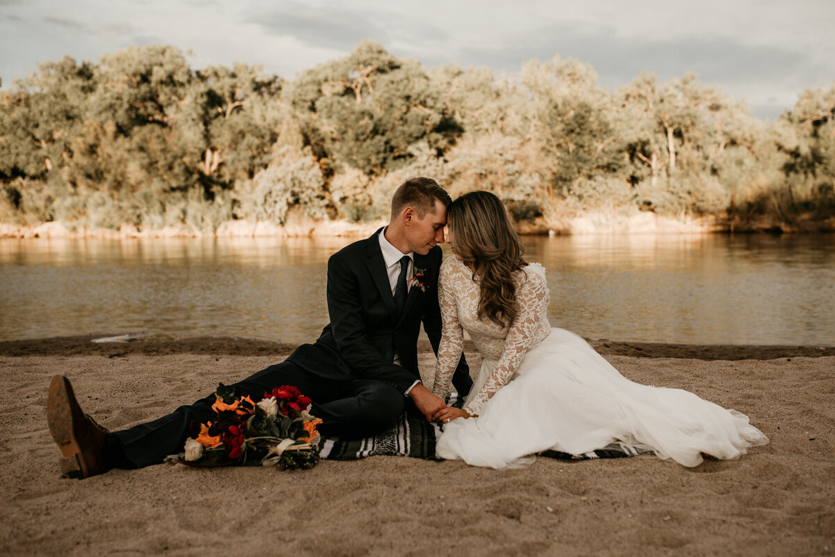 bride and groom sitting by the river