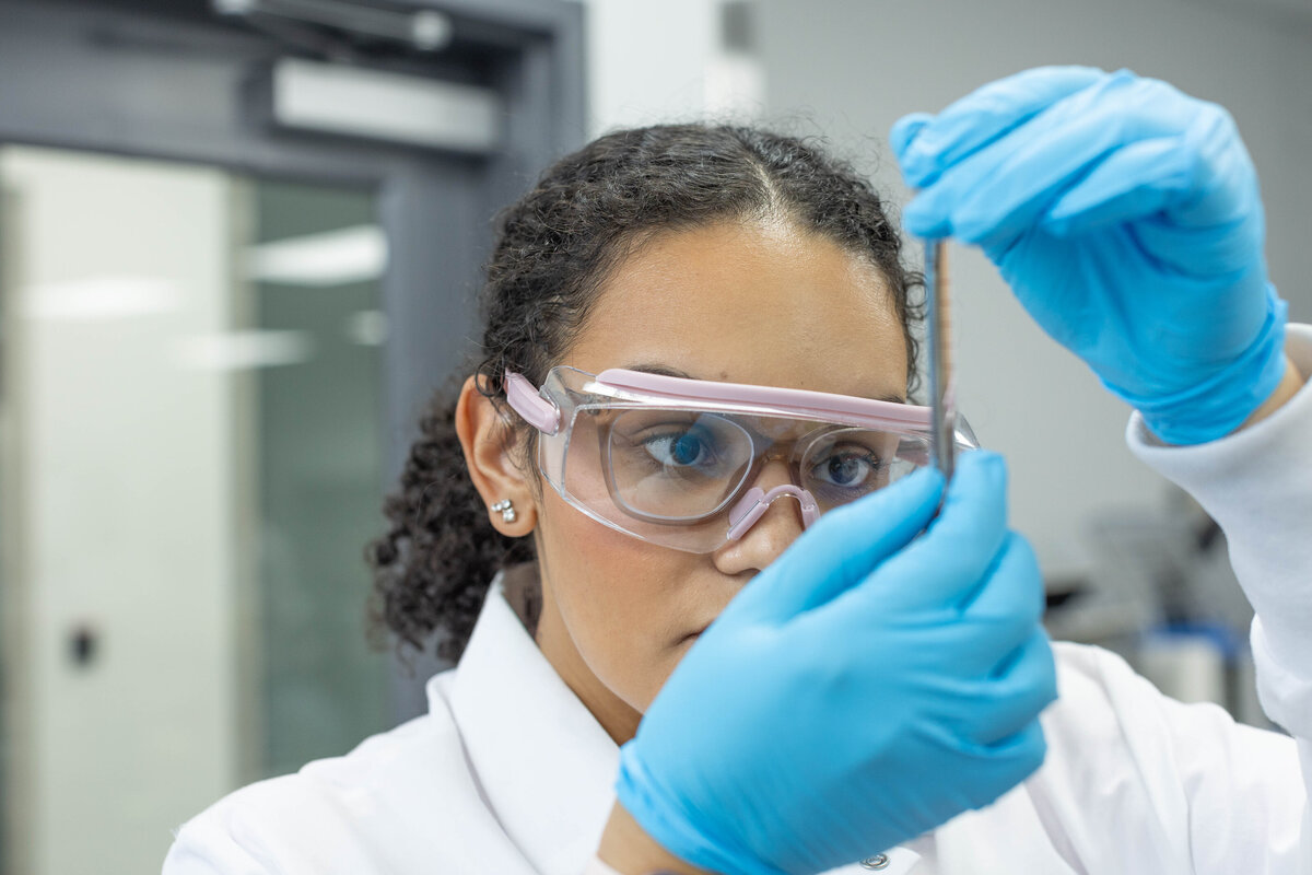 Female Scientist looking at a test tube with safety goggles on