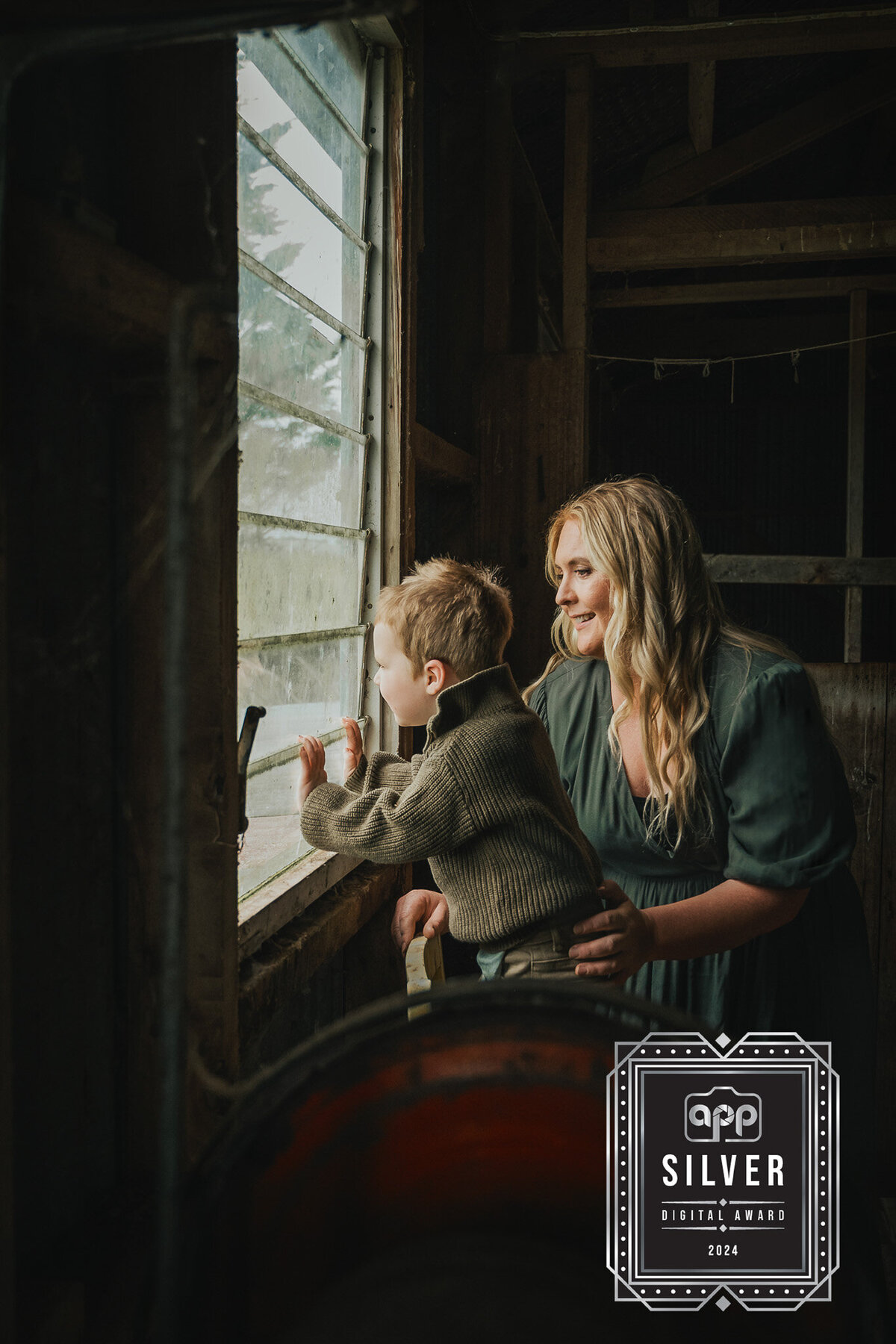 Mum and her son looking out an old woolshed window on their farm