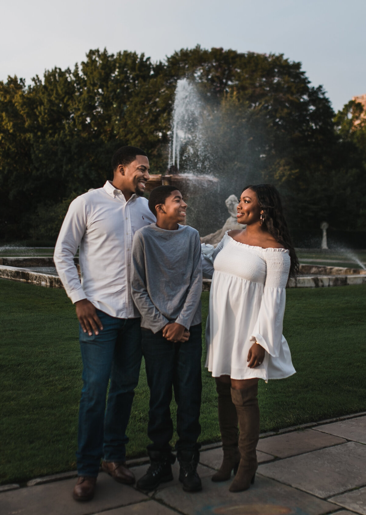 Pregnancy announcement photoshoot with a mom, dad, and child standing outside.