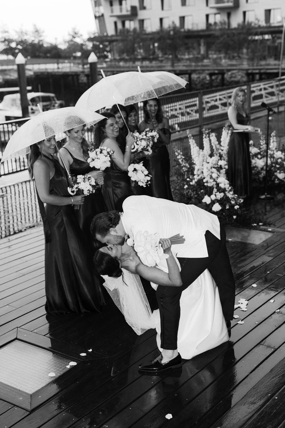 Bride and groom kiss bridesmais hold umbrella
