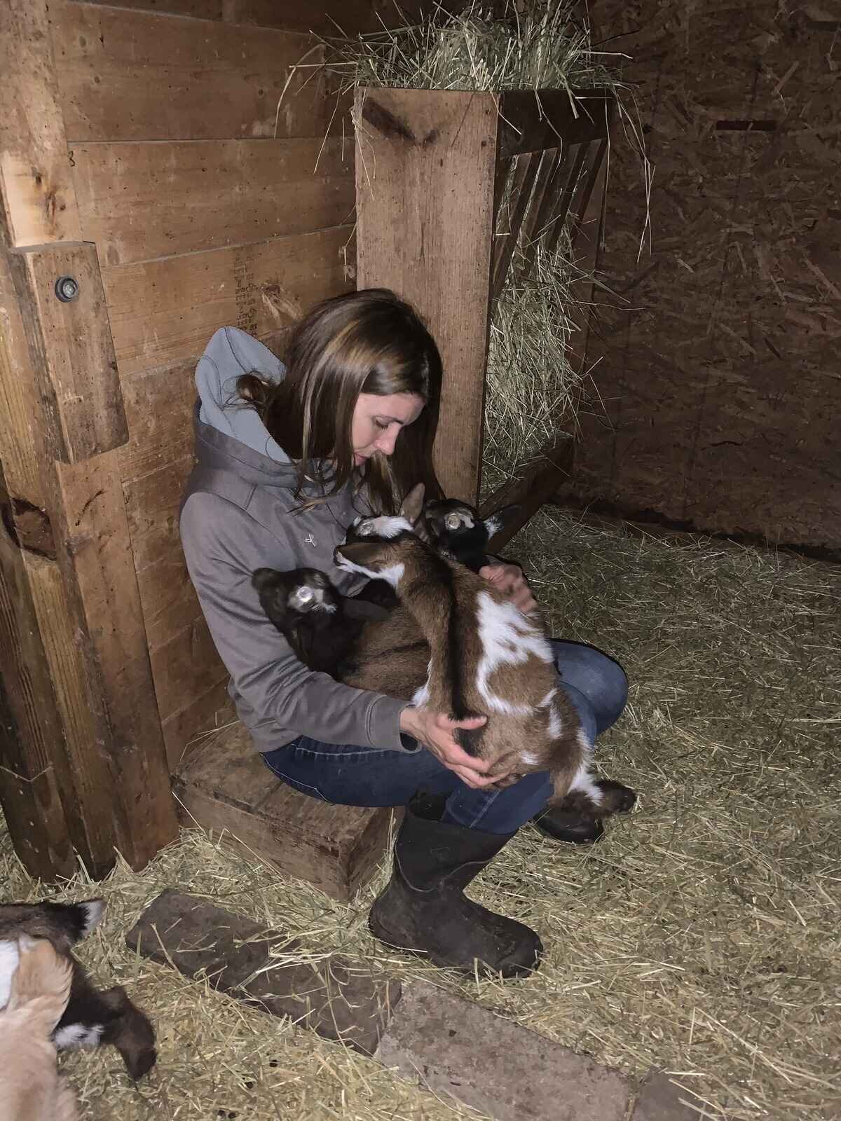 women-holding-nigerian-dwarf-goats-in-barn