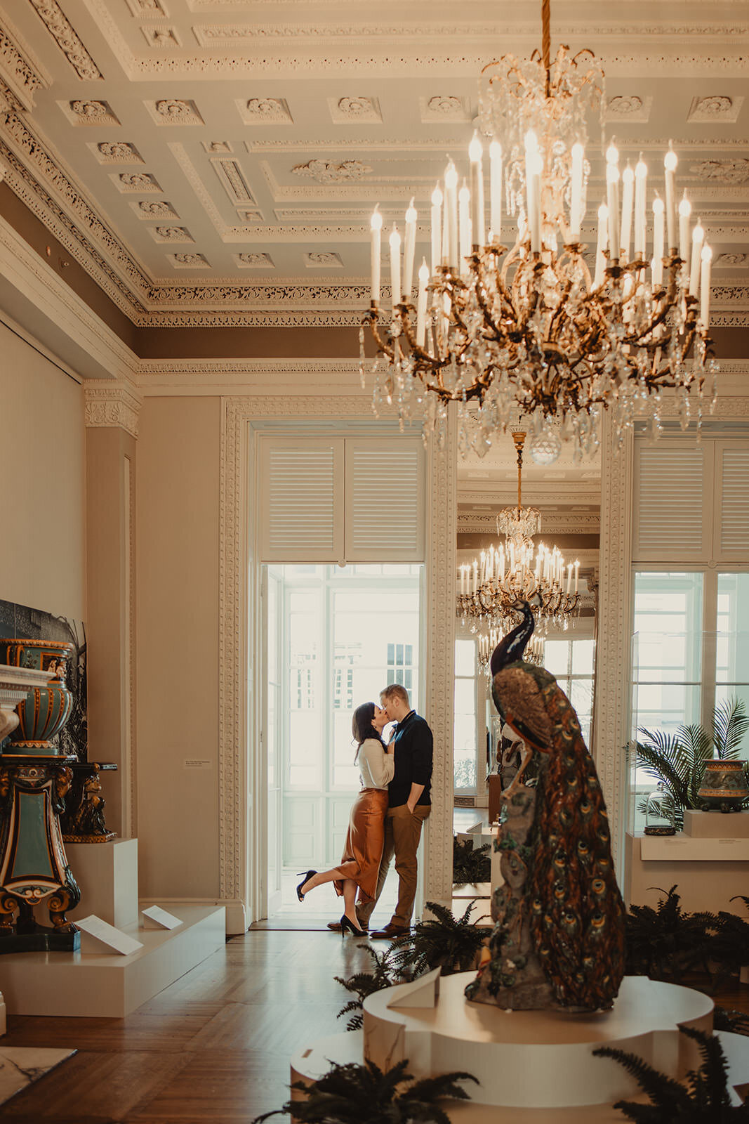 A coupe kissing in a doorway of an elaborate room 