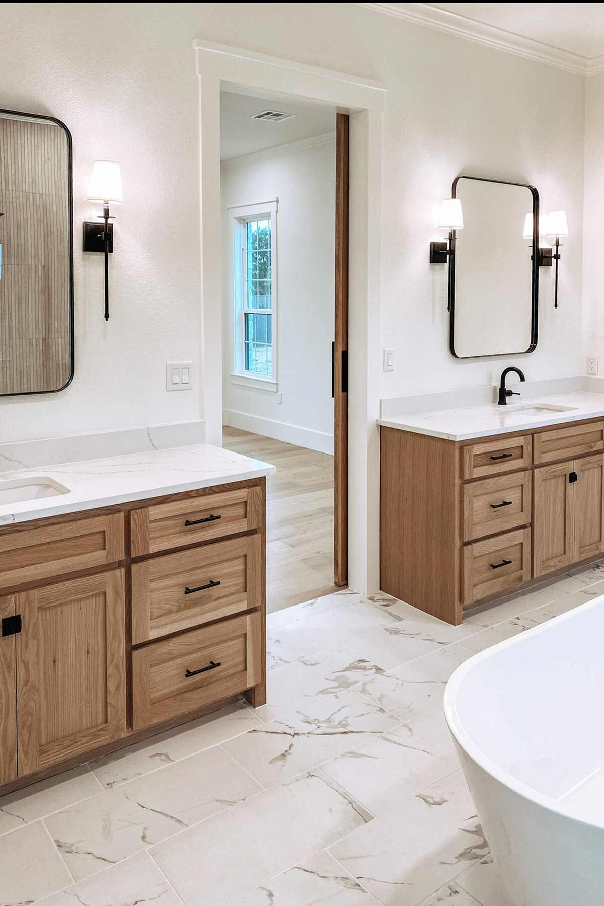 two wood vanities with white countertops and light fixtures on either side of mirrors