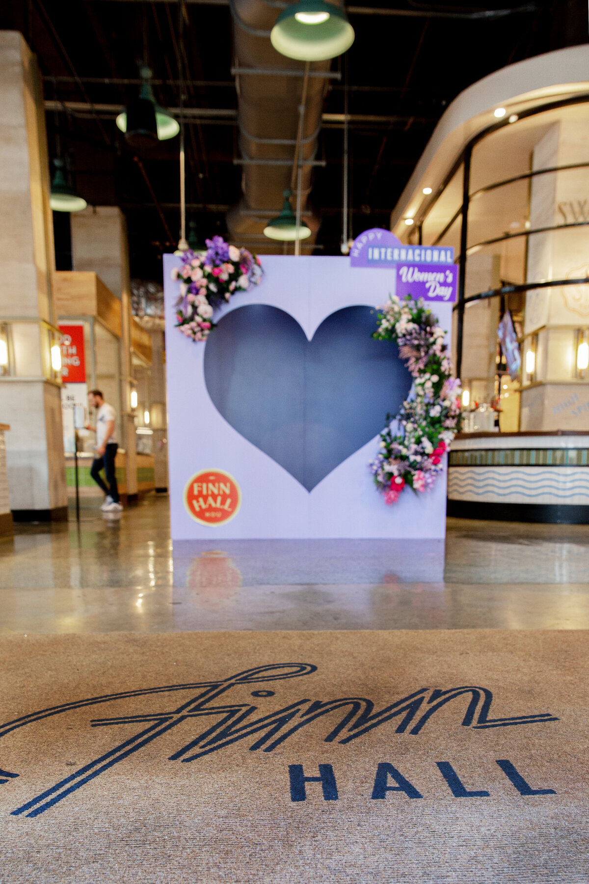Purple heart shaped photo booth backdrop display decorated with florals for International Women's Day
