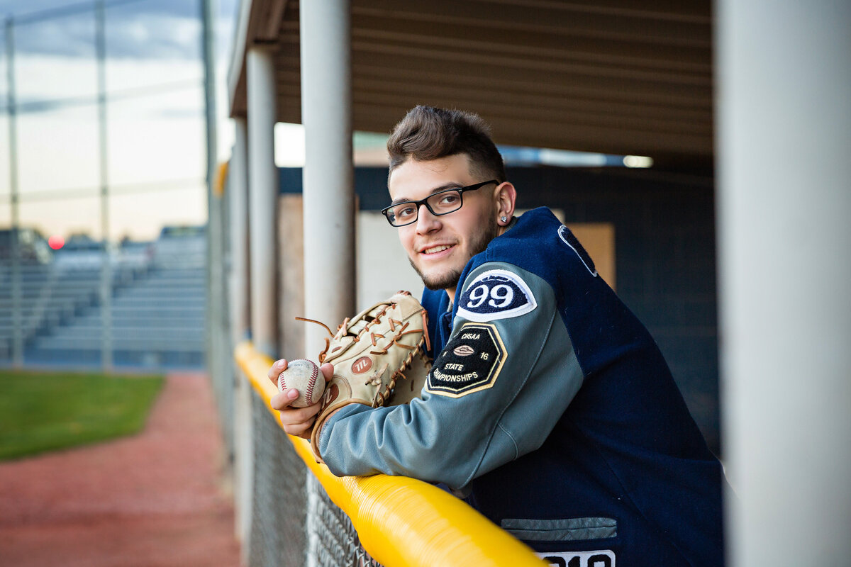 Senior guy in a letter jacket with baseball glove in a dugout
