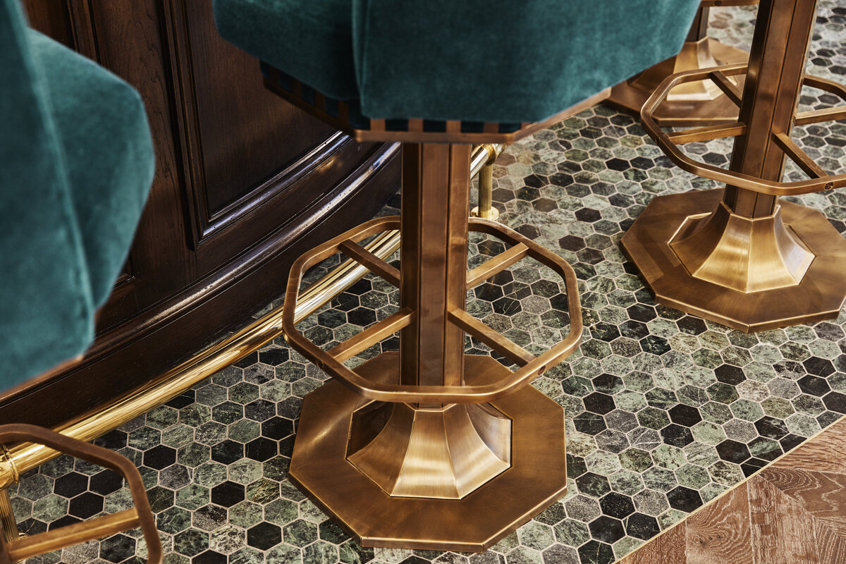 Bar stool with geometric shaped brass base and velvet upholstery