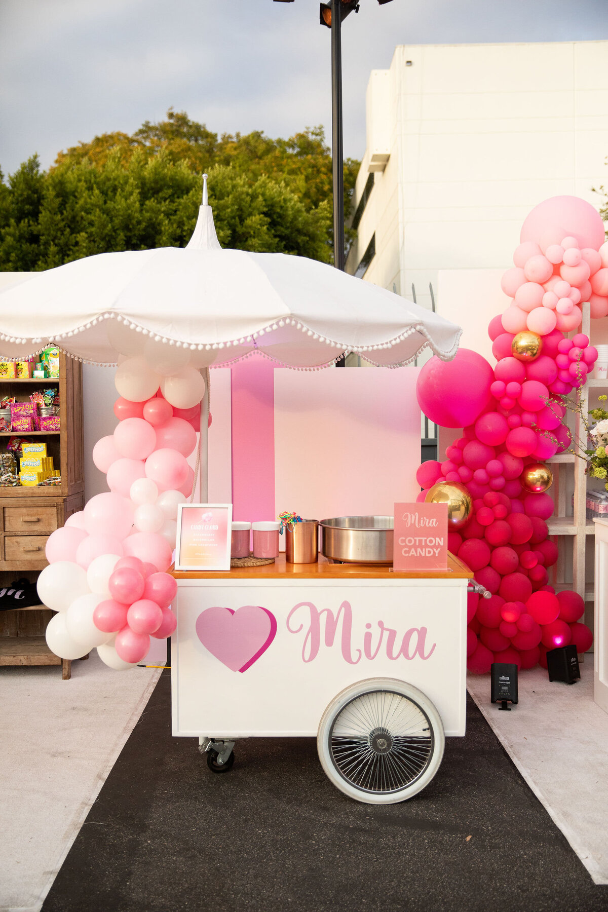 A vendor cart with pink balloons and a pink heart