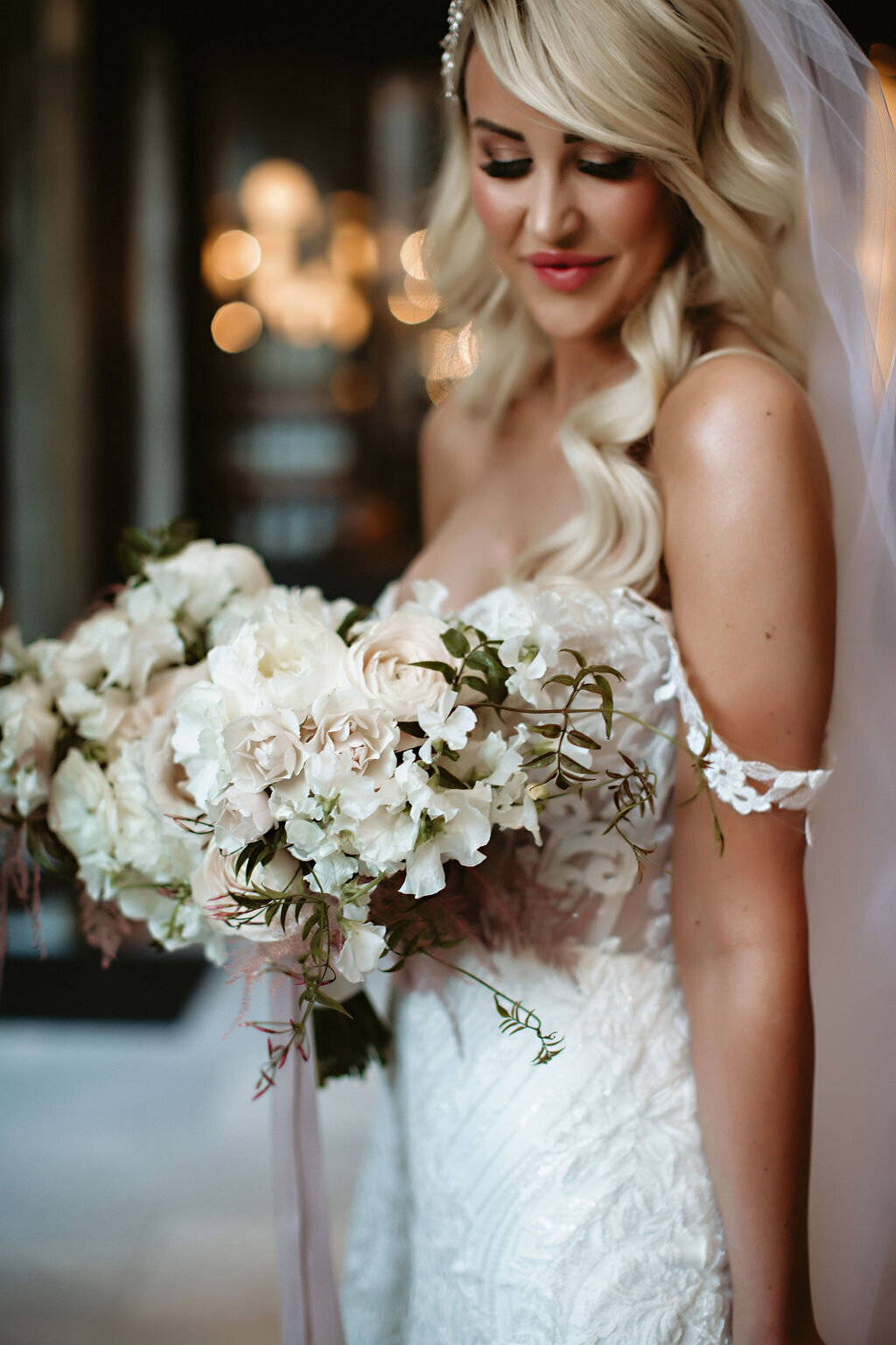 Bride posing with her bouquet in lace wedding gown.