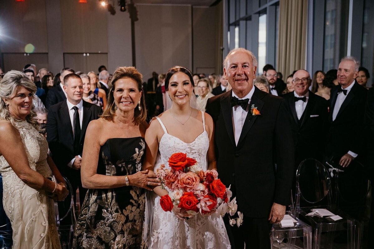 bride processing down the aisle with her parents holding pink and red cascade bouquet by Philadelphia wedding florist Sebesta Design