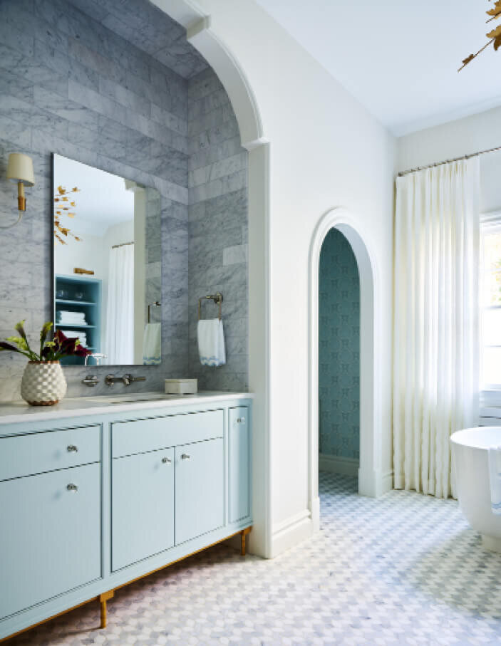 Interior decorators in Boston designed a traditional Milton bathroom remodel with blue custom cabinets and Visual Comfort light fixtures for a timeless look.