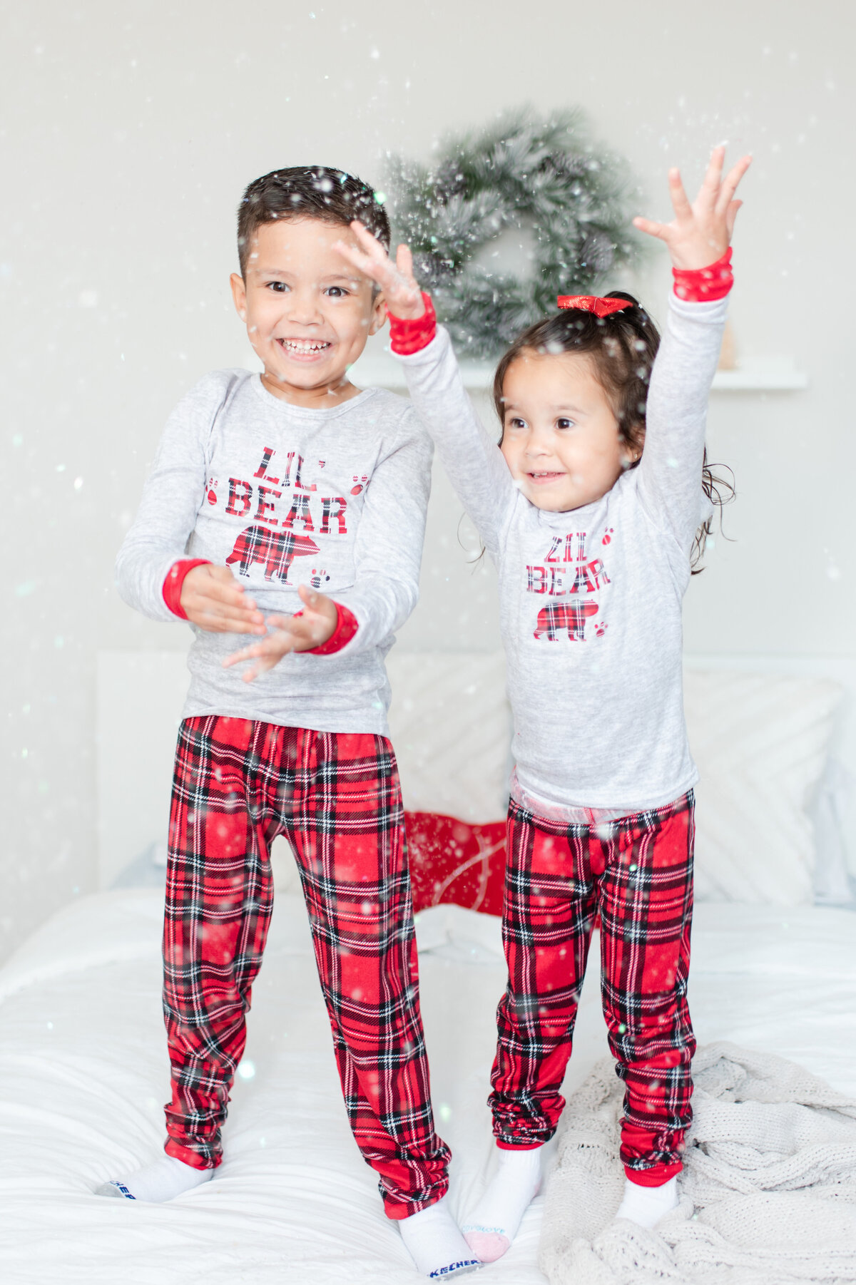 toddler siblings brother and sister jumping on the bed with snow and pajamas by miami christmas mini session photographer msp