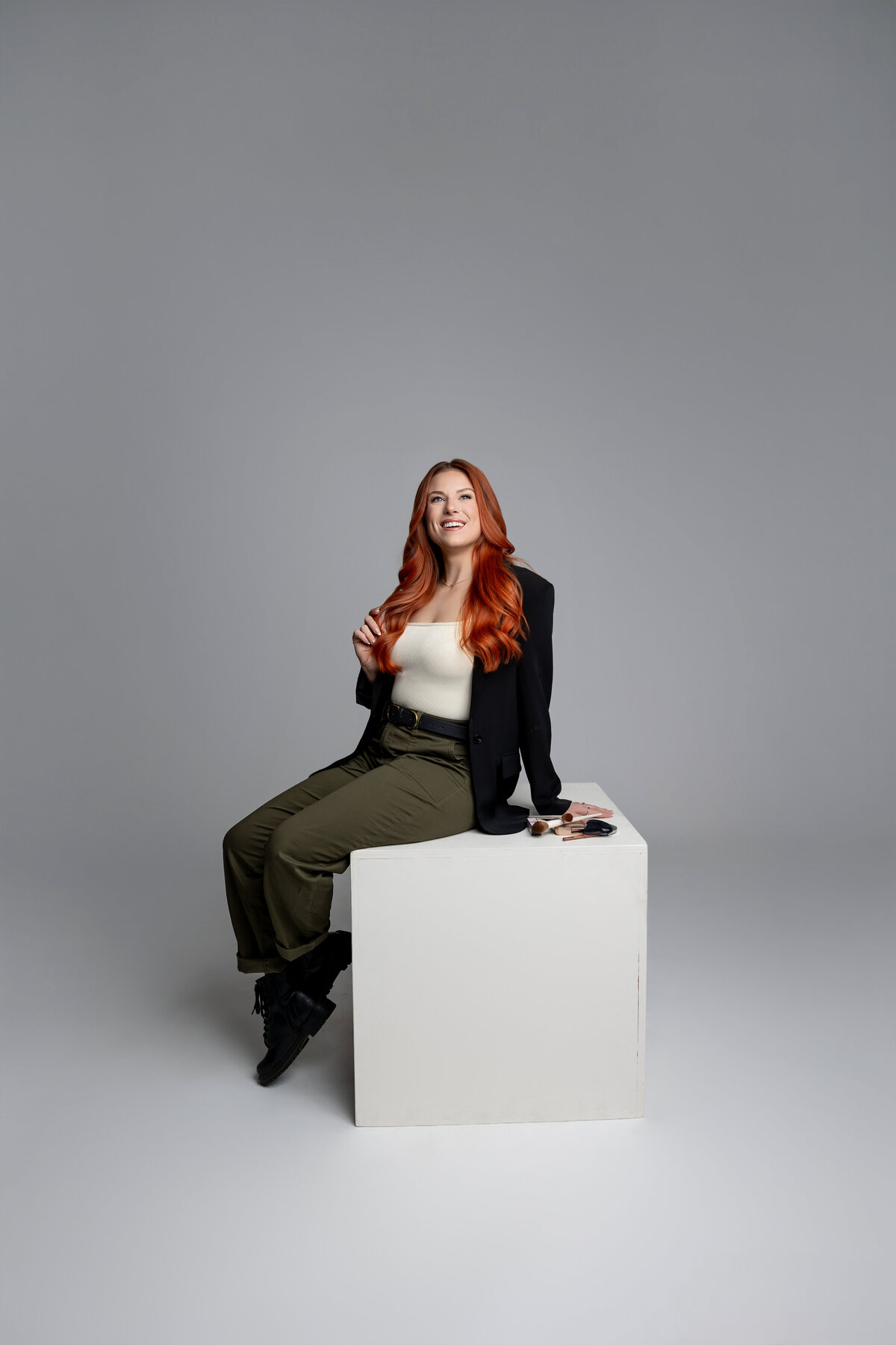 Woman with red hair sitting casually on a white cube in studio branding session. Photograph by Yucaipa branding photographer Kaitlyn Dawn Photography.