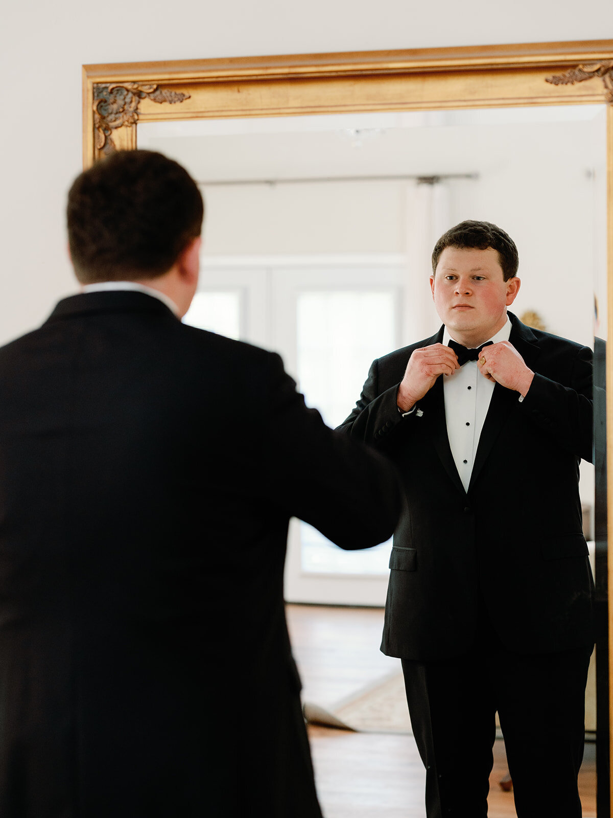 Groom get ready in front of the mirror on his wedding day.