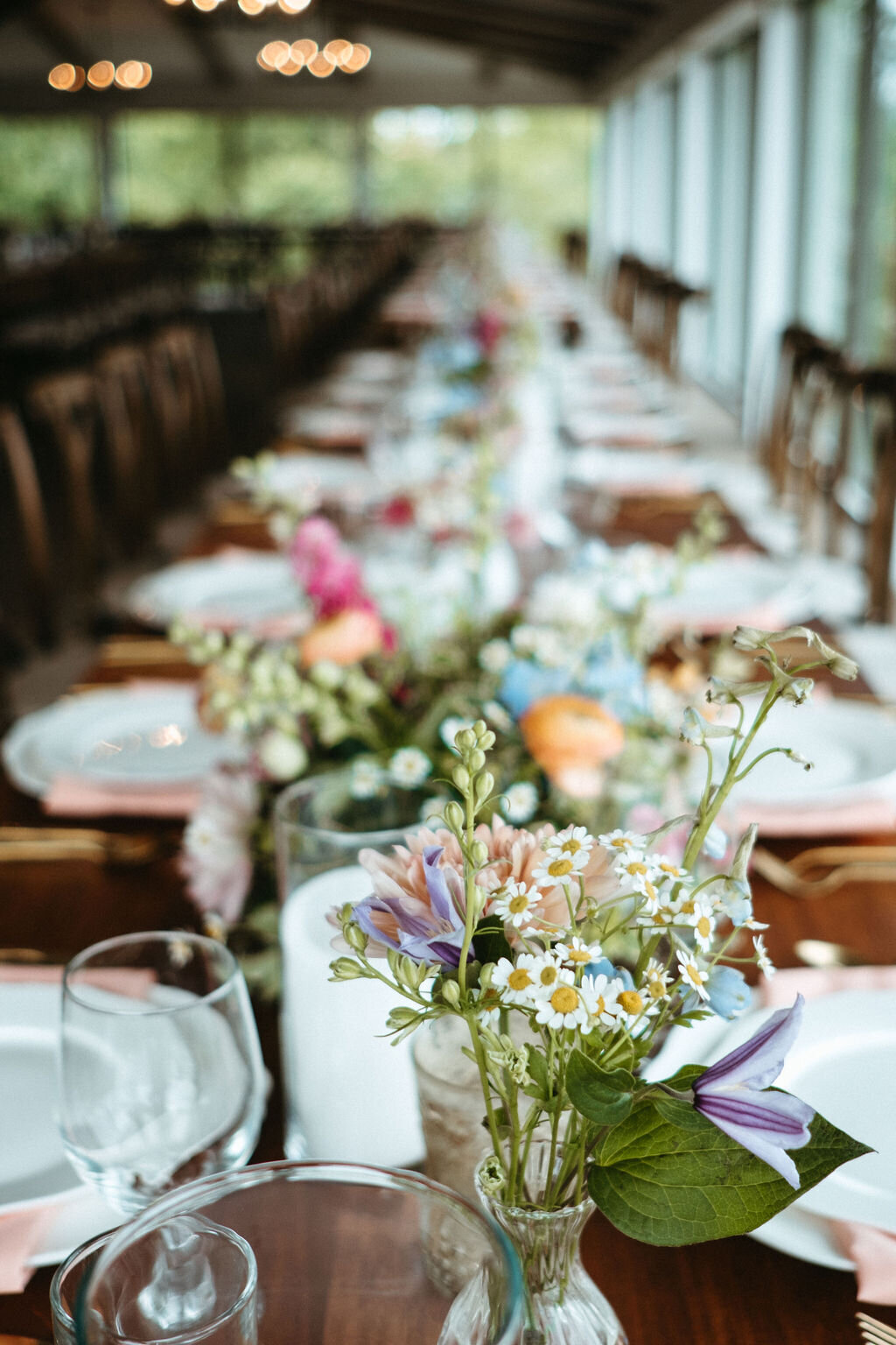 wildflowers grace the dining tables at a reception at Willowbrook wedding venue with white china