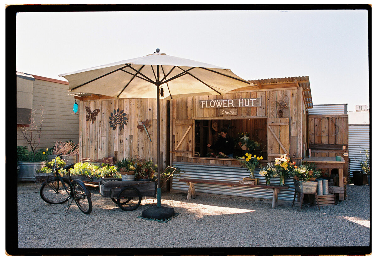 Flower hut captured on film by Kate Winters Photography, showcasing the charm and authenticity of the scene in a documentary style.