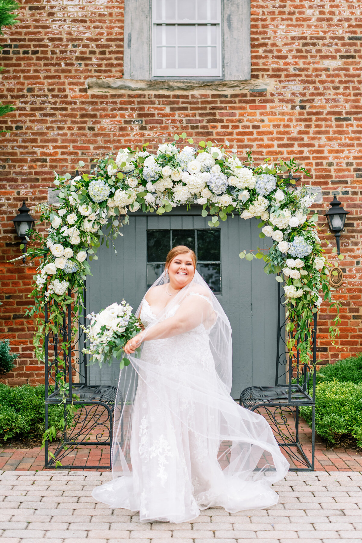 Bride in front of large blue and white arch at wedding venue in Leesburg, VA