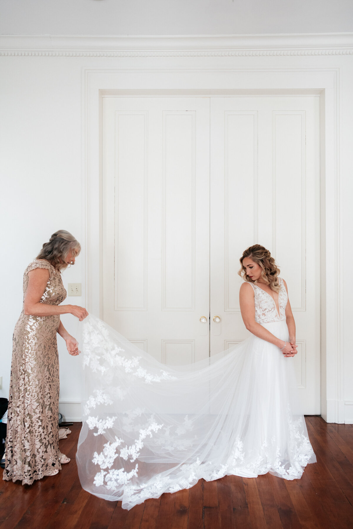 mother and bride putting on gown