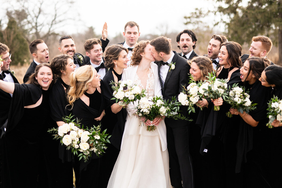 Bride and groom kissing in front of wedding party