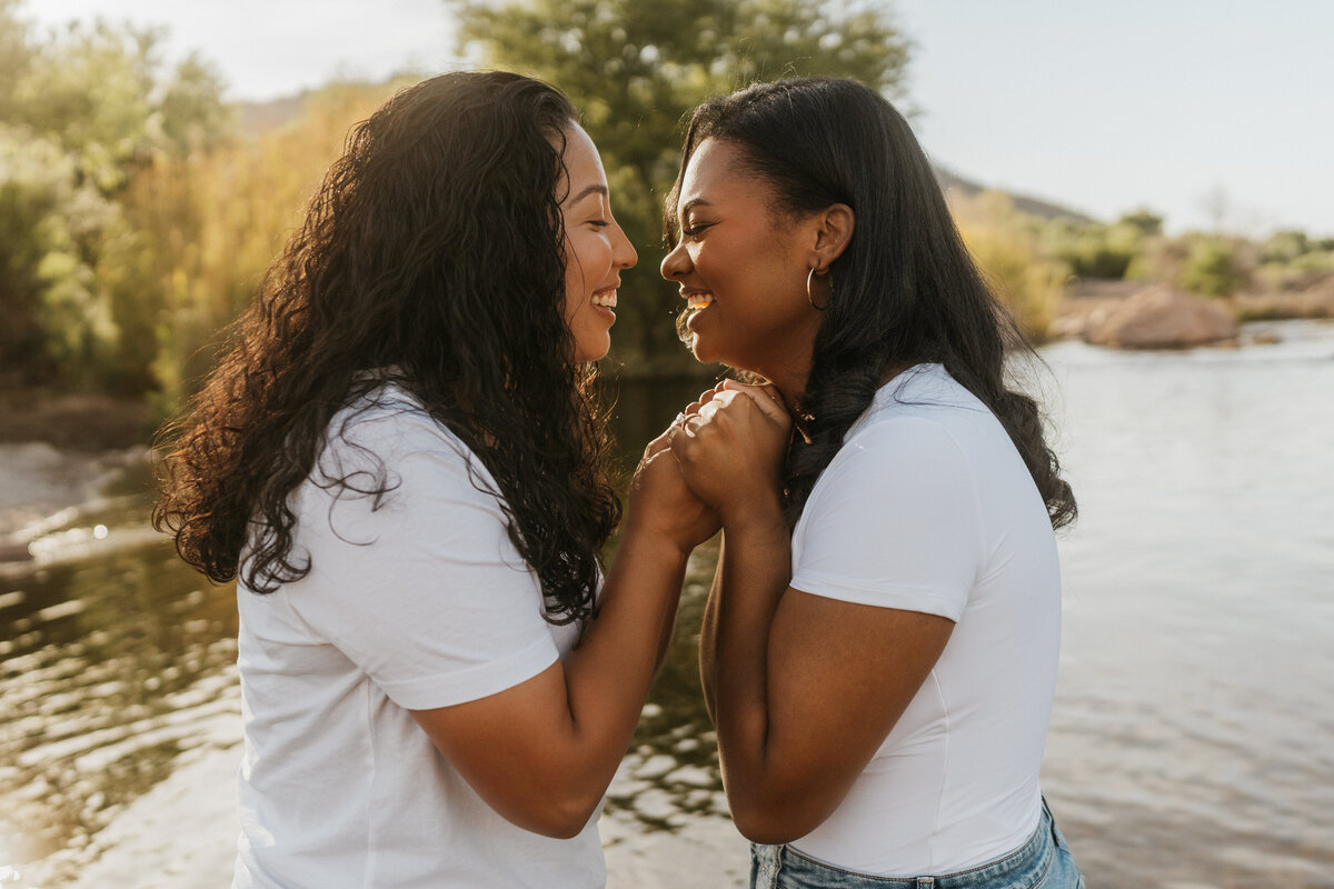 A couple holding their hands between them and smiling at each other 