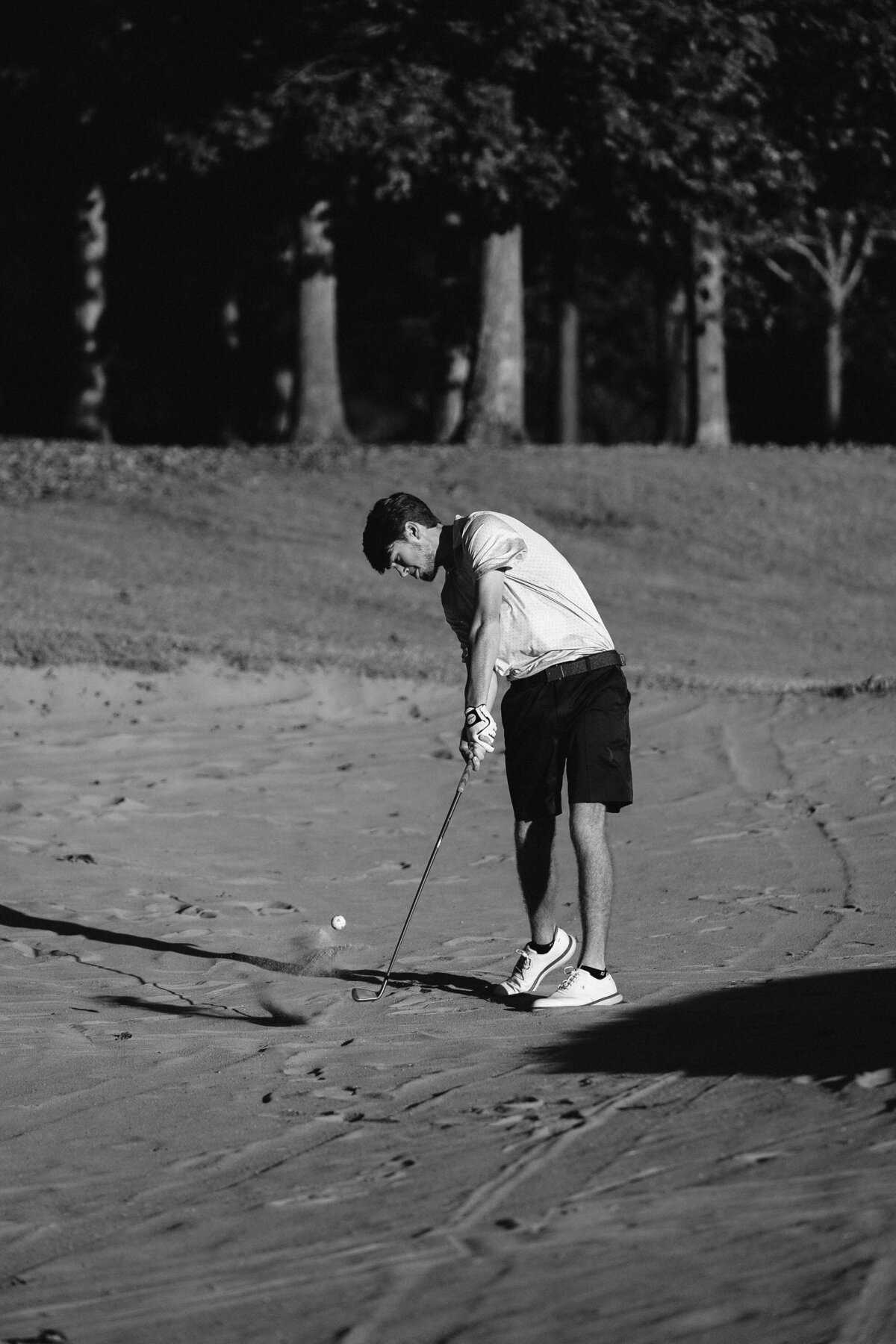 High contrast black and white photo of Senior golfer Keegan Jones hitting ball out of sand trap at Devil's Ridge in Holly Springs, NC in October 2021.
