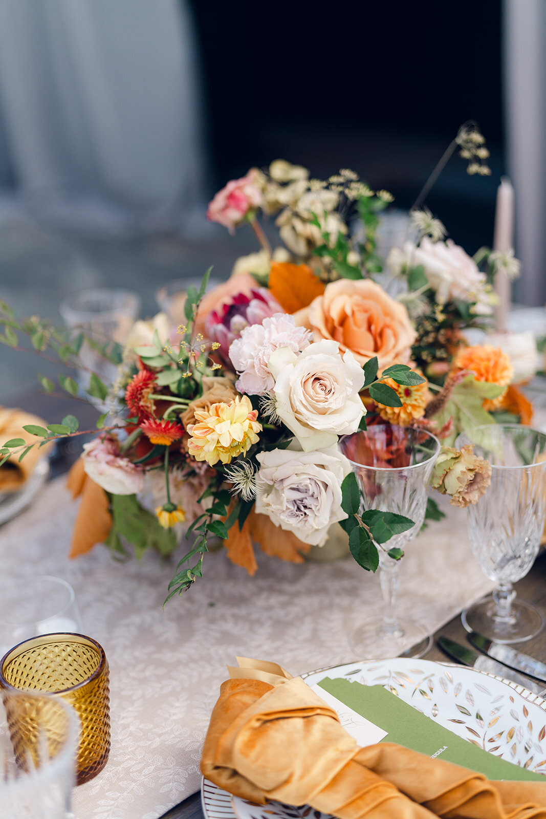 Tasteful fall florals for private property wedding in the foothills of Tennessee. Black rimmed clear tent wedding in Nashville, TN. Fall floral centerpieces consisting of dahlias, roses, fall foliage, and protea. Fall wedding colors in rust, copper, sage, gold, and hunter green. Unique pleated and textured candles for wedding tables. Design by Rosemary & Finch Floral Design in Nashville, TN. 
