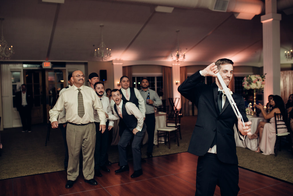 Wedding Photograph Of Men Looking At The Groom Stretching The Wedding Garter Los Angeles