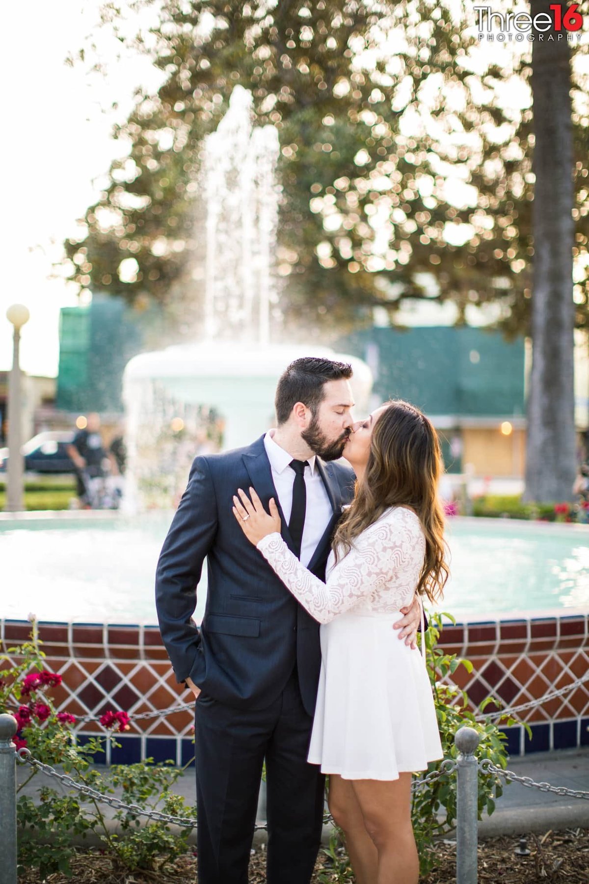 Engaged couple share a kiss while standing in front of the Old Towne Orange water fountain