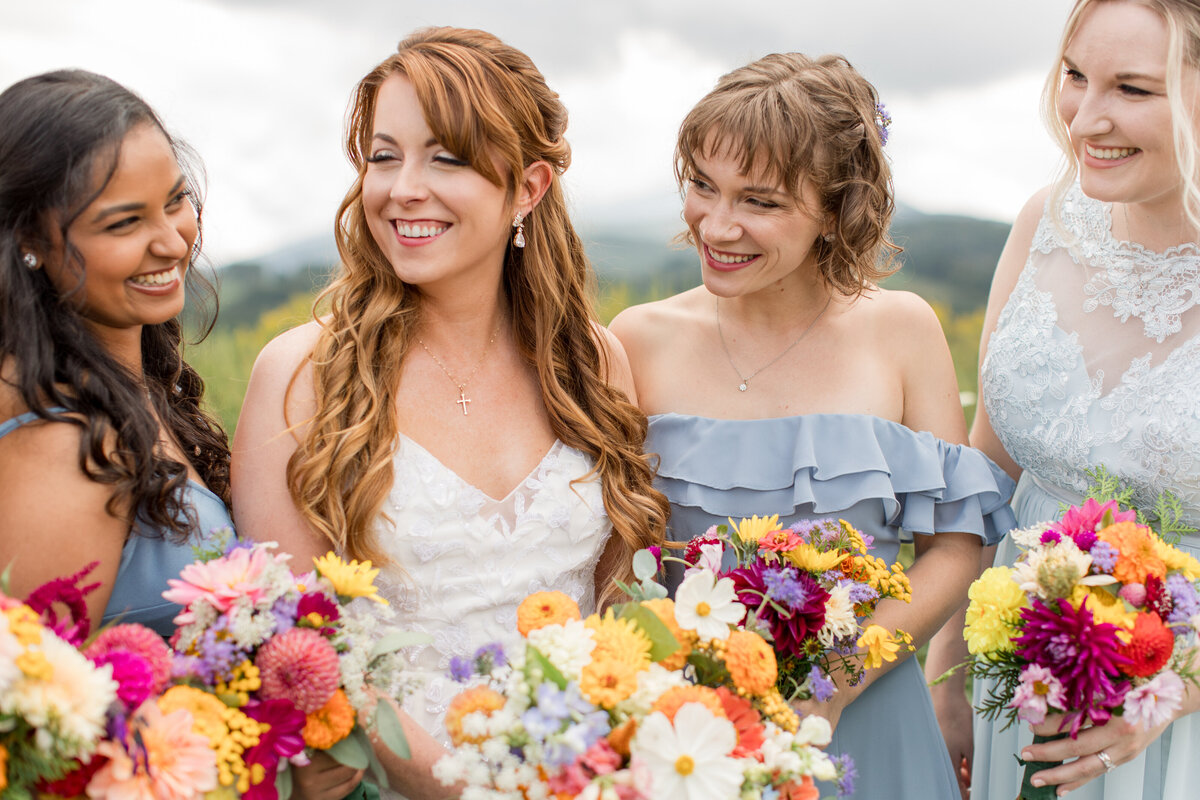 Wedding party photo in Boone, NC of a bride and her bridesmaids smiling and laughing at each other.