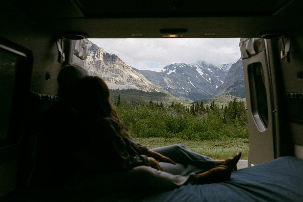 Couple admiring the beauty of Glacier National Park from their camper van in Many Glacier