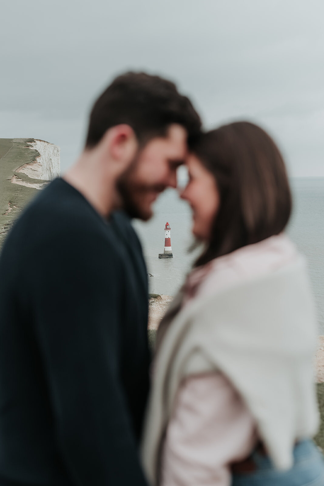 Couple forehead to forehead with Beachy Head Lighthouse in the background