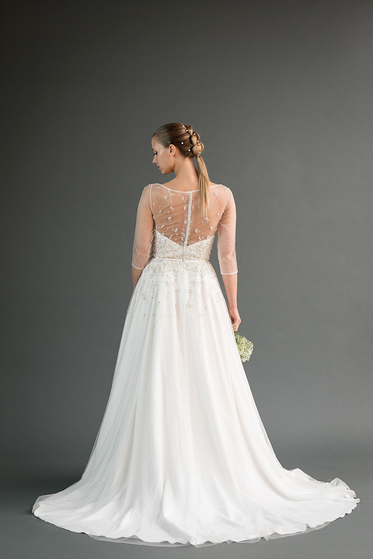 The back view of the Rei wedding dress style which has an a-line skirt, illusion neckline, and sheer three-quarter sleeves.
