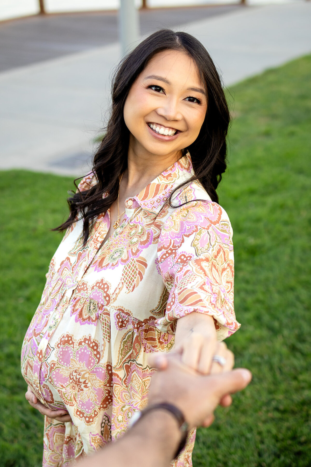 Expecting mother gazes lovingly at her partner while holding hands during a joyful outdoor maternity shoot — Bay Area Maternity Portfolio - Ellobelle Photography.