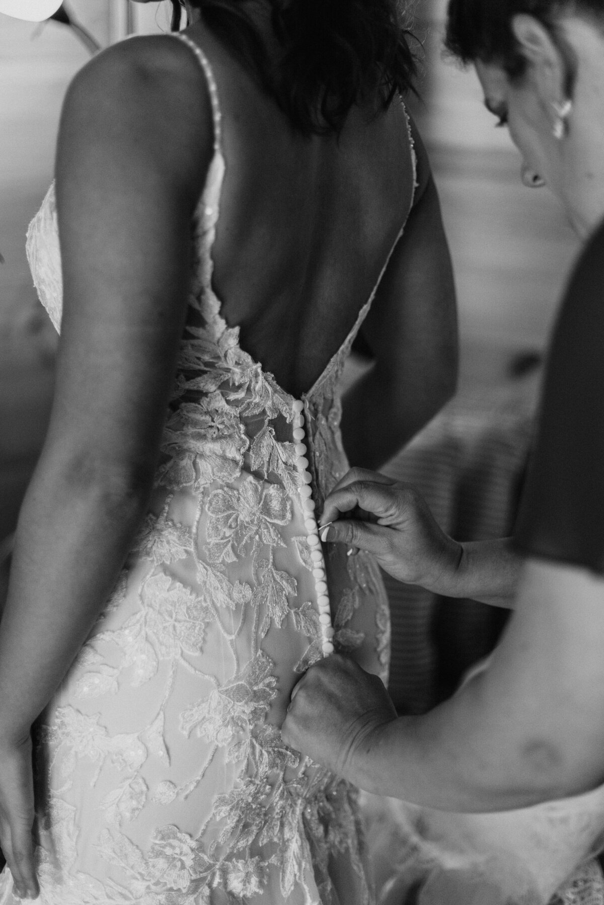 person zipping up the back of a bride's wedding dress