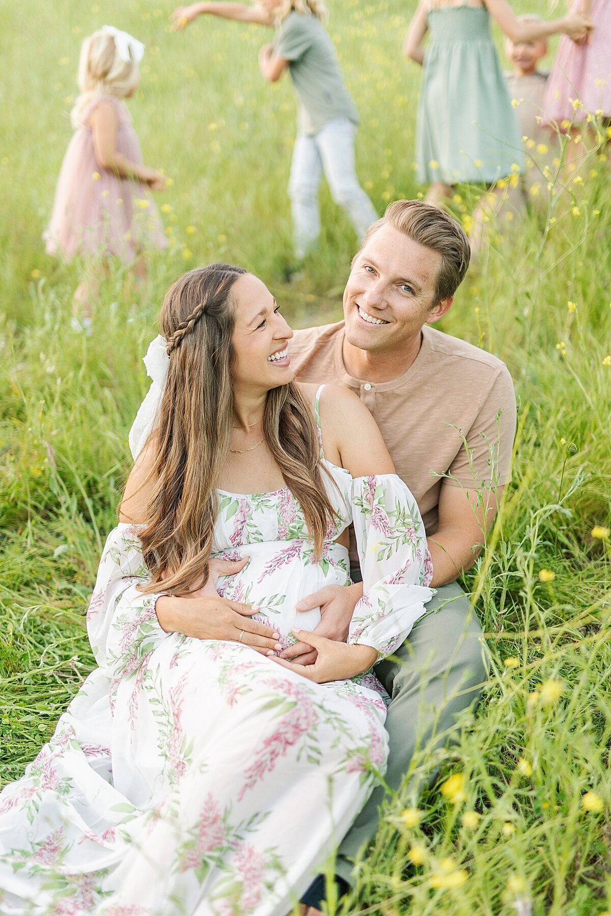 Children playing behind mom and dad at maternity photography session in San Marcos, California.